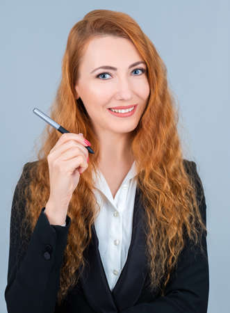 Redhead woman holding a graphic pen. She is wearing a suit.の写真素材