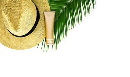Golden cream bottle, a hat and tropical leaf on the white background.