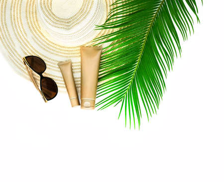 Golden cream bottles, a hat and tropical leaf on the white background.