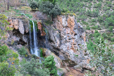 A large beautiful waterfall in a forest with blue water and trees.の写真素材