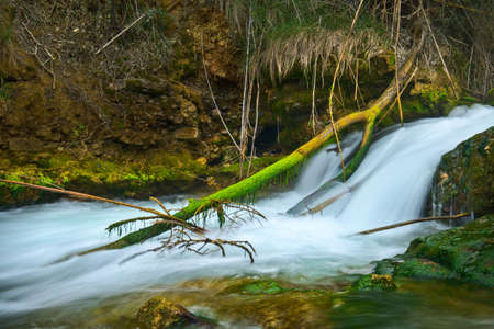 A beautiful waterfall in a forest with blue water and trees.の写真素材