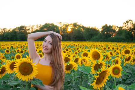 Sunflowers field on sunset. Woman with a long hair is dancing.の写真素材