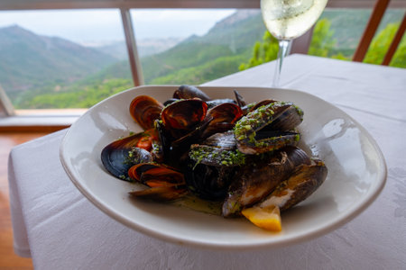 Tasty mussels on a table with a glass of a fine white wine.の写真素材