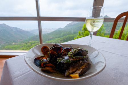 Tasty mussels on a table with a glass of a fine white wine.の写真素材