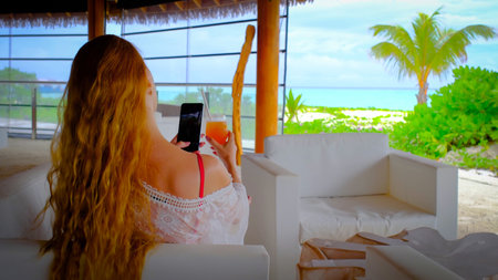Woman with a mobile phone and a cocktail. Happy female on Maldives.の写真素材