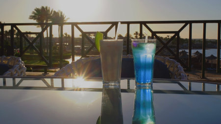 Two cocktails is standing on a glass table.の写真素材