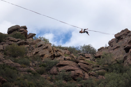 A person is balancing on a tightrope stretched between rocky cliffs.の写真素材