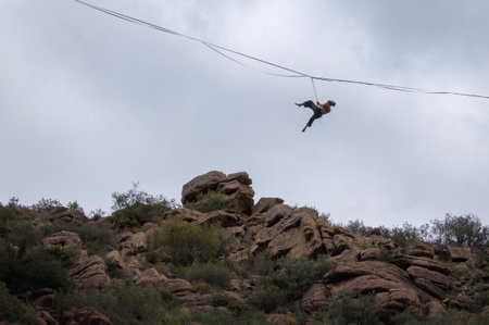A person is balancing on a tightrope stretched between rocky cliffs.の写真素材