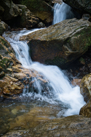 A close-up view of a small waterfall flowing over moss-covered.の写真素材