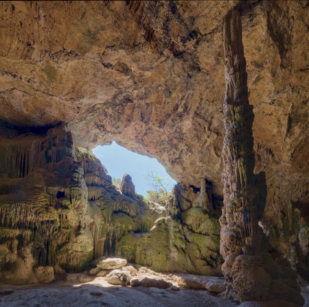 natural cave with sunlight streaming through an opening, highlighting intricate rock formations.の写真素材