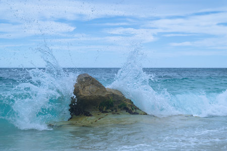 This image captures an ocean wave crashing against a rock, with water.の写真素材