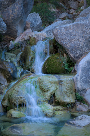 A serene waterfall flows gently over moss-covered rocks.の写真素材