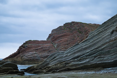 This image shows dramatic, layered rock formations along the rugged coastline of northern Spain.の写真素材