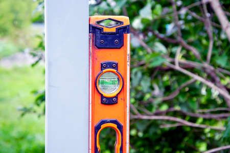 Measuring the level of installation of a metal post with a building level. Fence construction, repair work. lose up macroの写真素材