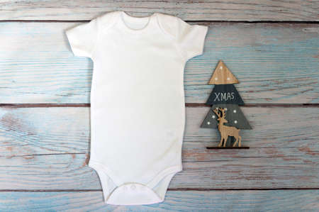 Christmas White baby bodysuit mockup on wooden background. Styled stock photography. Mock up.の写真素材