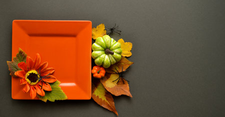 An orange square plate with a sunflower on a gray background with pumpkins, leaves, and spiders....