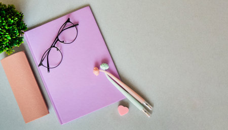 Notebook on light gray background with pens. Glasses with case.