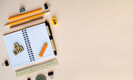 Open notebook on beige background, stationery, pens, pencils, ruler