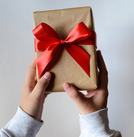 A box, a gift with a red bow in hands.の写真素材