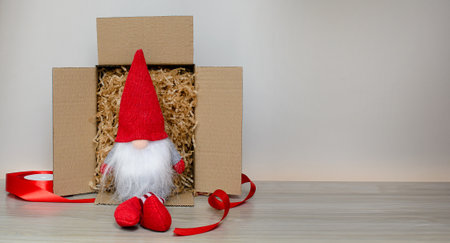 A toy gnome sits in a box on a gray background. Giftの写真素材