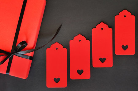A red box with a black bow on a black background. Space for inscription.の写真素材