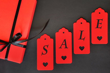 A red box with a black bow on a black background. Inscription Saleの写真素材