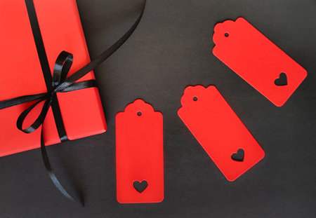 A red box with a black bow on a black background. Space for inscription.の写真素材