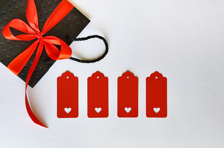 Black bag with a red bow on a white background with space for textの写真素材