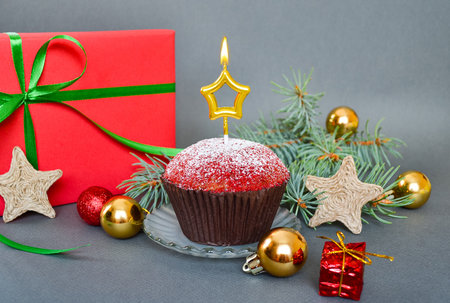 Christmas cupcake with a candle on a gray background. Gift, Christmas tree branches, and decorations.の写真素材