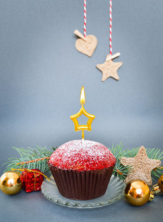 Christmas composition with cupcake and candle, on grey background.の写真素材