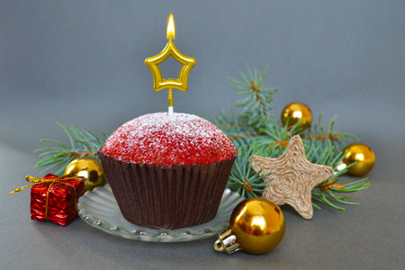Christmas composition with a cupcake and a candle, on a gray background.の写真素材