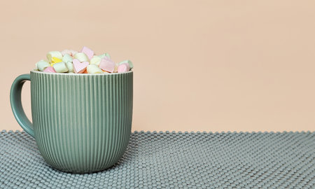A gray cup with marshmallows on a beige background. Space for text.の写真素材