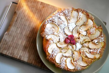 Apple pie sprinkled with icing sugar decorated with raspberriesの写真素材
