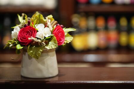 Bouquet of white and red flowers in a light ceramic vase on tabletopの写真素材