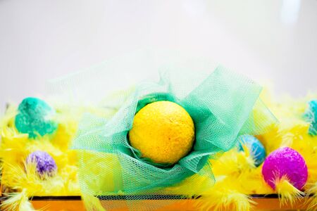 Easter coloful eggs and yellow feathers in the basketの写真素材