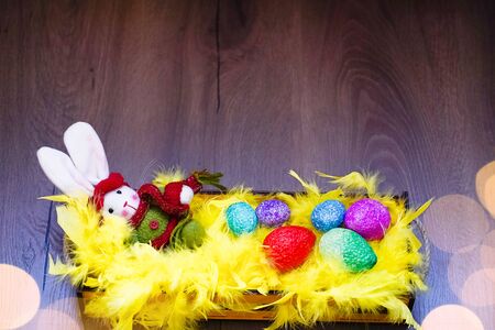 Easter bunny, coloful eggs and yellow feathers in the basket.の写真素材