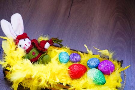 Easter bunny, coloful eggs and yellow feathers in the basket.の写真素材