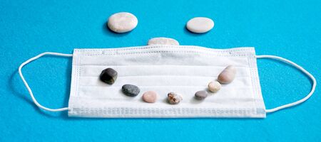 Medical face mask and shells on a blue background. Tourism crisis