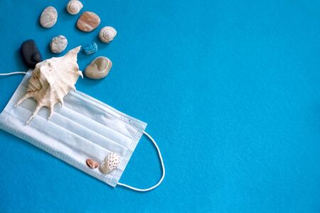 Medical face mask and shells on a blue background. Tourism crisisの写真素材