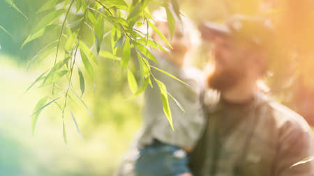 Blurred summer famely concept. dad and daughter smile on the background of trees, foliage. High...