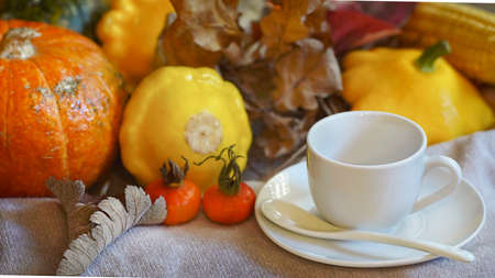 Blurred Cozy autumn composition. White ceramic mug with beige knitted sweater surrounded by autumn...
