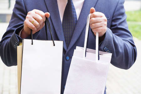 a man in a suit holding packages in his hands. High quality photo