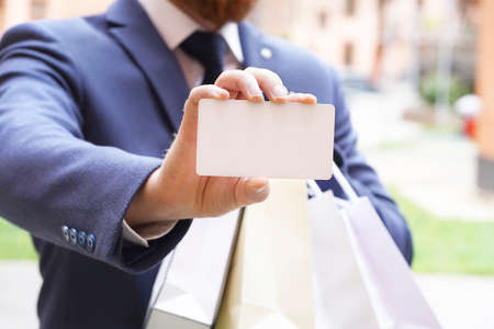 Blurred man in a suit holding Black card and packages in his hands. High quality photoの写真素材