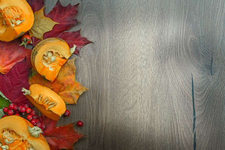 Autumn harvest composition with Cut pumpkin and maple leaves on wooden background. High quality...