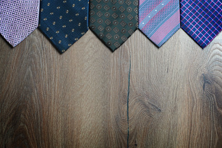 Multi-colored neckties on a brown wooden background with copy spaceの写真素材