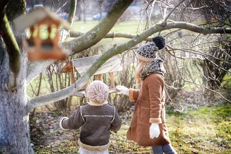 Blurred View of girls feeding birds in spring, birdhouse. High quality photoの写真素材