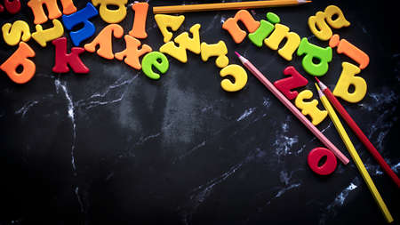 Black blackboard background with coloful letters of the english alphabet. Flat lay supplies with copy space. Back to school concept. ... High quality photoの写真素材