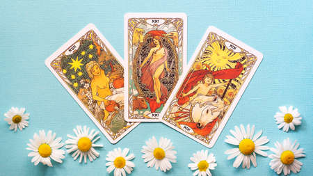 View of Golden tarot cards on the Blue background with Daisy flowers. High quality photo