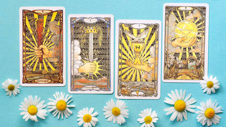 View of Golden tarot cards on the Blue background with Daisy flowers. High quality photo