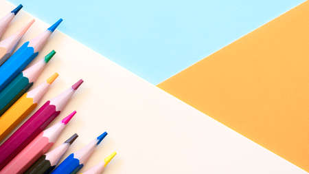 Multi colored pencils on empty sheet, Pastel colored blue, peach and orange tones. High quality photoの写真素材